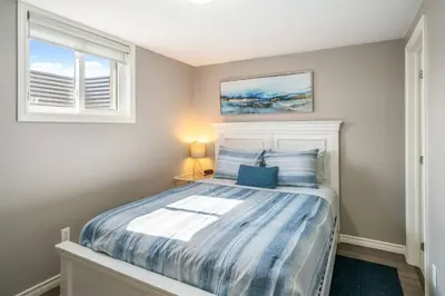 a bedroom with a bed with a blue comforter at Single Level Vineyard Home | 6 PPL | Pet Friendly in Niagara on the Lake