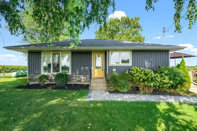 a home with a yellow door and green grass at Single Level Vineyard Home | 6 PPL | Pet Friendly in Niagara on the Lake