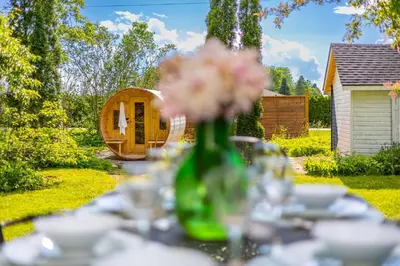 a table with a vase with flowers in a yard at Top 5% Sauna | Bocce Ball | Vineyard Views | NOTL in Niagara on the Lake