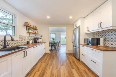 a kitchen with white cabinets and a wooden floor at Top 5% Sauna | Bocce Ball | Vineyard Views | NOTL in Niagara on the Lake