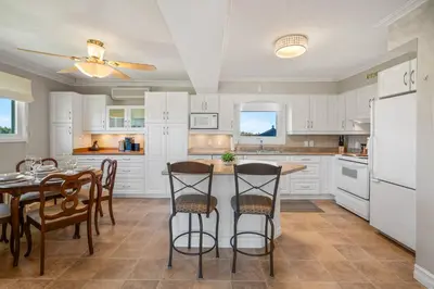 a kitchen with white cabinets and a table and chairs at Vineyard Home Pet Friendly NOTL Large Backyard in Niagara on the Lake