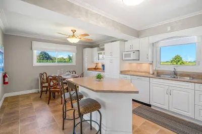 a kitchen with white cabinets and a table with chairs at Vineyard Home Pet Friendly NOTL Large Backyard in Niagara on the Lake