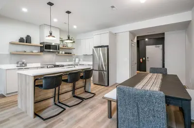a kitchen with white cabinets and a table and chairs at 1 Bdrm Luxe Apartment in Niagara in Niagara on the Lake