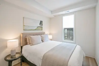 a white bedroom with a bed and a window at 2 Bdrm Brand New Luxe Niagara Apt - up to 6ppl in Niagara on the Lake