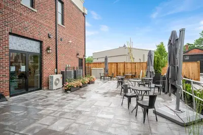 a patio with tables and chairs and a brick building at 2 Brdm Modern Brand New Niagara Apt up to 6 ppl in Niagara on the Lake