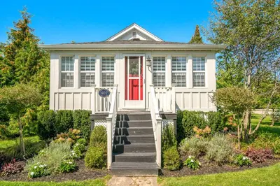 a white house with a red door at Walk to Old Town | Cottage 3 ppl Top 10% | Parking in Niagara on the Lake