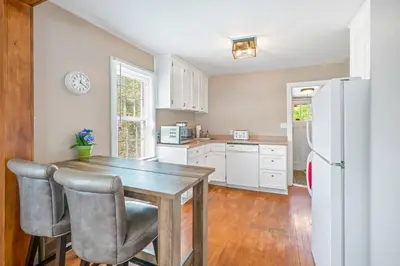 a kitchen with a wooden table and a refrigerator at Walk to Old Town | Cottage 3 ppl Top 10% | Parking in Niagara on the Lake