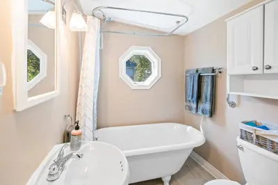 a bathroom with a white tub and a sink at Walk to Old Town | Cottage 3 ppl Top 10% | Parking in Niagara on the Lake