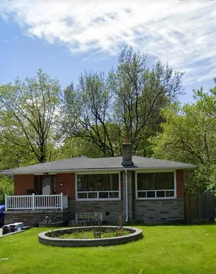 a small house with a porch and a yard at Rayann Hospitality in Toronto