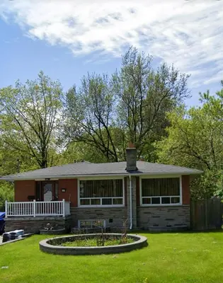 a small house with a porch and a yard at Hanan Hospitality in Toronto