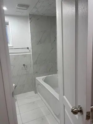 a white bathroom with a tub and a sink at Hanan Hospitality in Toronto