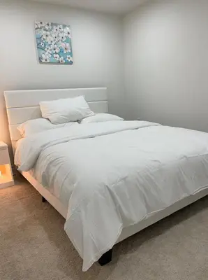 a white bed in a white room with at Hanan Hospitality in Toronto