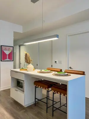 a kitchen with a large white island with stools at Deluxe Suites Downtown Toronto in Toronto