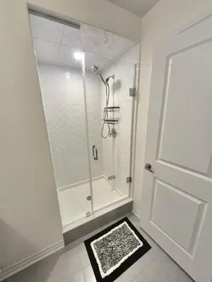 a white bathroom with a shower with a glass door at First Class Ensuite Room in Brantford