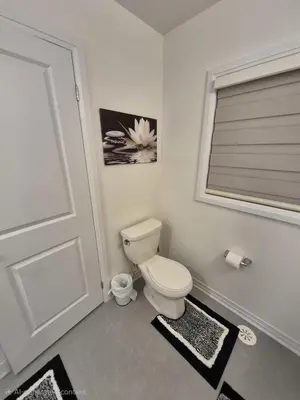a bathroom with a toilet and a window and a door at First Class Ensuite Room in Brantford