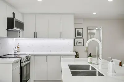 a white kitchen with white cabinets and a sink at The Wynford Dreamy Capri Suite in Elora