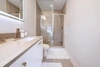 a white bathroom with a shower and a toilet at Charming Mississauga Getaway in Mississauga