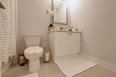 a white bathroom with a toilet and a mirror at Charming Mississauga Getaway in Mississauga