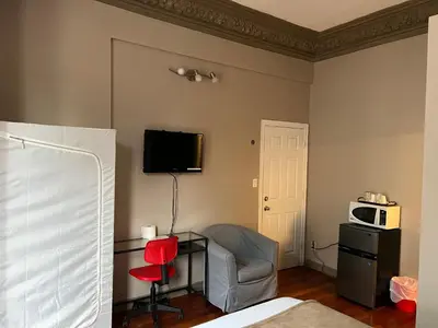 a bedroom with a chair and a desk and a microwave at Klaus Guesthouse in Toronto