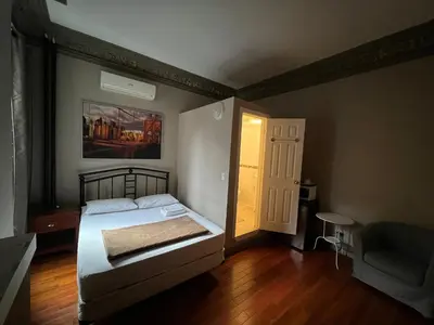 a bedroom with a bed and a chair and a door at Klaus Guesthouse in Toronto
