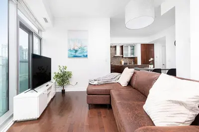 a living room with a brown couch and a tv at 2 bedrooms Downtown Toronto Free parking in Toronto