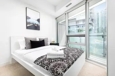 a bedroom with a white bed and a large window at 2 bedrooms Downtown Toronto Free parking in Toronto