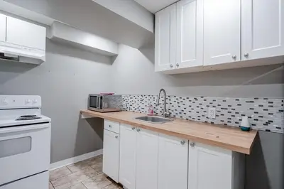 a kitchen with white cabinets and a sink at Renovated 2 Bedroom Basement Apartment Near 401 and Amenities in Bowmanville