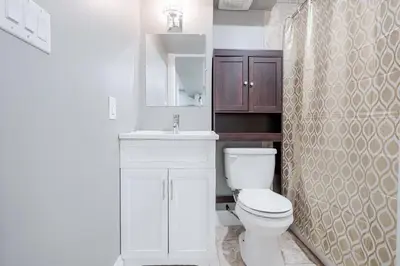 a white bathroom with a toilet and a sink at Renovated 2 Bedroom Basement Apartment Near 401 and Amenities in Bowmanville