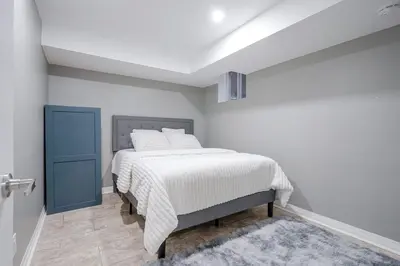 a white bedroom with a bed with white sheets at Renovated 2 Bedroom Basement Apartment Near 401 and Amenities in Bowmanville
