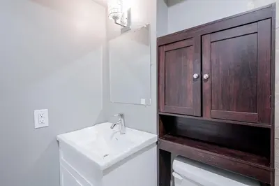 a bathroom with a sink and a wooden cabinet at Renovated 2 Bedroom Basement Apartment Near 401 and Amenities in Bowmanville