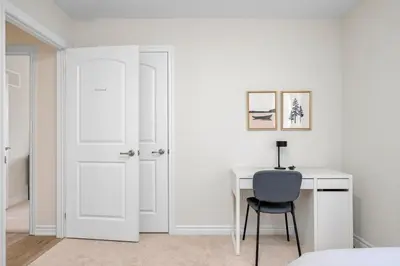a white bedroom with a desk and a blue chair at Stylish and Cozy Muskoka Vacation Home in Gravenhurst