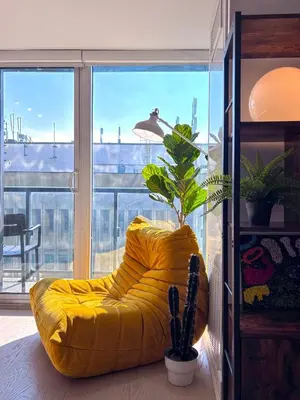 a yellow chair in a room with a large window at DT Cozy 1B1B with Den near UofT and Bay St in Toronto