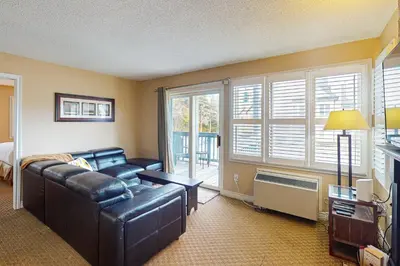 a living room with a leather couch and a bed at Condo 701 at North Creek Resort in Blue Mountains
