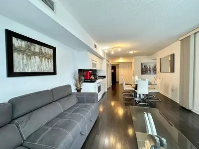 a living room with a gray couch and a kitchen at Spacious two-bedroom abode in the heart of TO in Toronto