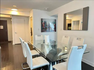 a dining room with a glass table and white chairs at Spacious two-bedroom abode in the heart of TO in Toronto