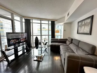 a living room with a couch and a flat screen tv at Spacious two-bedroom abode in the heart of TO in Toronto