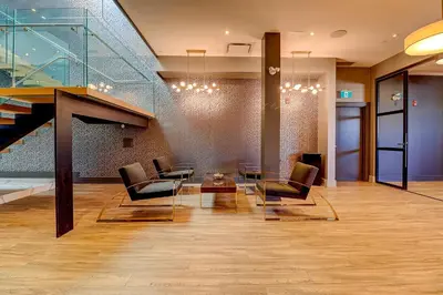 a lobby with chairs and a table and a staircase at Dream Suites Near YYZ Airport in Mississauga