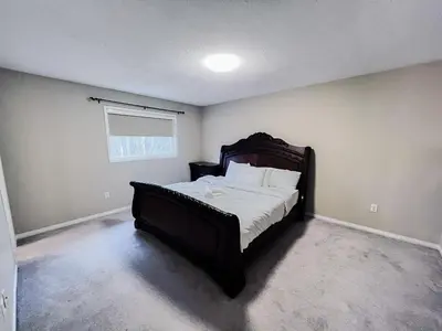 a bedroom with a bed with white sheets and a window at Family Comfort Retreat in Brampton