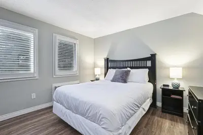 a bedroom with a large bed and two windows at 109 North Creek in Blue Mountains