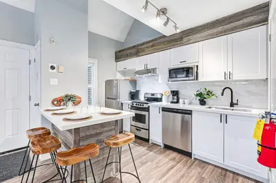 a kitchen with white cabinets and a kitchen island with stools at 109 North Creek in Blue Mountains