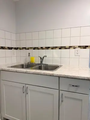 a kitchen counter with a sink and white cabinets at Modern Cozy Basement Suite Free Parking in Brampton