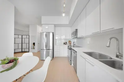 a kitchen with white cabinets and a stainless steel refrigerator at Tranquil Lakeside Suite Toronto in Toronto