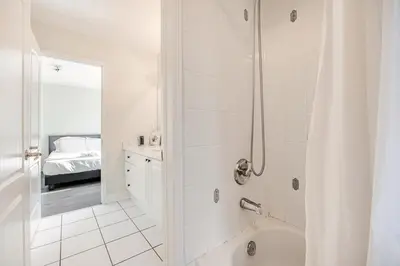 a white bathroom with a shower and a bed at Comfortable Brampton Getaway 3BR, 3BA, 4 Beds in Brampton