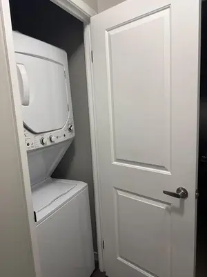 a white door leading into a bathroom with a washer and dryer at One-Bedroom Apartment with Den With Amazing Views of Hamilton in Hamilton