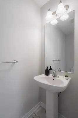 a white bathroom with a sink and a mirror at Airport/Family/3bdrm/5beds/4bath/Workspace/Hiking in Brampton