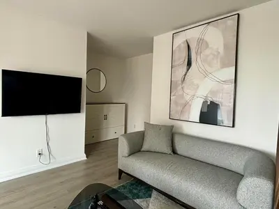 a living room with a couch and a flat screen tv at Elegant and Charm Superior Suite Yorkville Toronto in Toronto