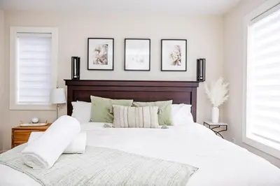 a bedroom with a large white bed with two windows at Relaxing Spa Getaway, Sauna, Hot Tub & Heated Pool in Blue Mountains