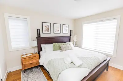 a bedroom with a large bed and two windows at Relaxing Spa Getaway, Sauna, Hot Tub & Heated Pool in Blue Mountains