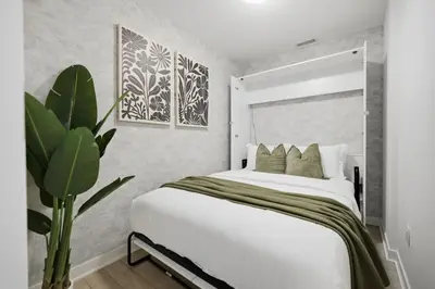 a bedroom with a large white bed and a plant at Stylish 2BR Retreat Parking & Sleeps 6 in Toronto