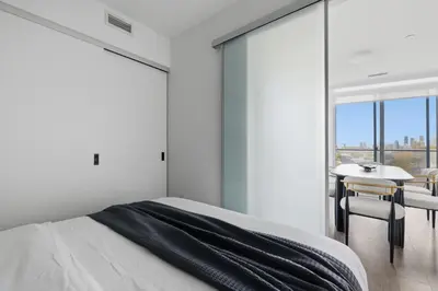 a bedroom with a bed and a table with chairs at Modern 3BR Condo Sleeps 8 with Floor-to-Ceiling Views in Toronto